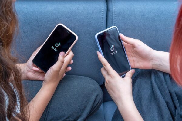 Two,Teenage,Girls,With,Phones,In,Their,Hands,Are,Sitting