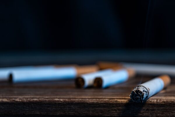 Burning,Cigarette,On,Wooden,Table,With,Smoke,,Tobacco,Addiction
