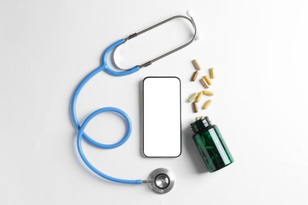 Telehealth.,Smartphone,,Stethoscope,And,Pills,On,Light,Background,,Flat,Lay
